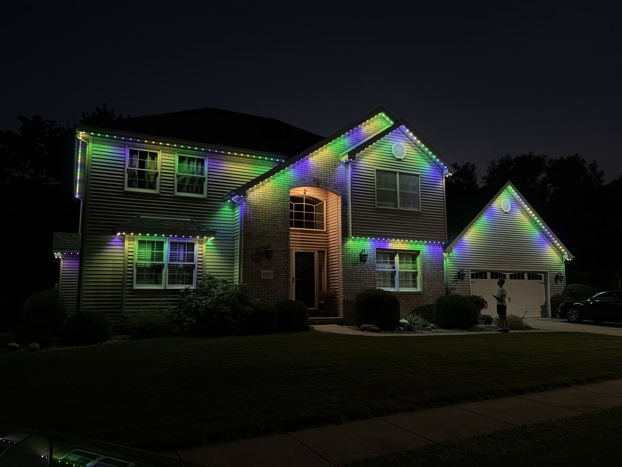 Sided home with multicolor green, purple and blue lighting outlining each roofline